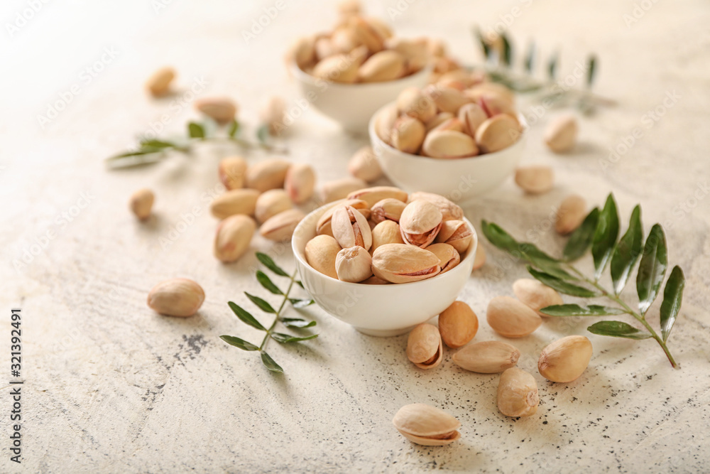 Bowls with tasty pistachio nuts on light background Bowls with tasty pistachio nuts on light background