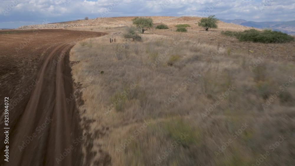Aerial over the dirt road with tire marks on the dry barren land. Forward moving. Aerial over the dirt road with tire marks on the dry barren land. Forward moving.