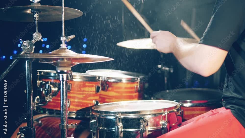 Person plays drums with water on them. Drummer plays drums kit. Person plays drums with water on them. Drummer plays drums kit.
