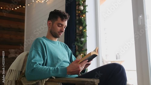 A man read a book sitting in a chair in a wooden house