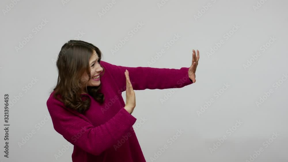 Phobia. Side view of frightened brunette woman in pullover shaking from fear and holding hands in defensive gesture, looking terrified and desperate. indoor studio shot isolated on gray background Phobia. Side view of frightened brunette woman in pullover shaking from fear and holding hands in defensive gesture, looking terrified and desperate. indoor studio shot isolated on gray background
