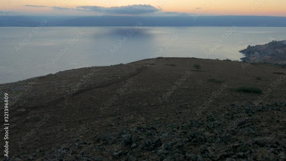 Aerial over the mountainous cliffs and calm ocean under cloudy sky at twilight. Forward moving. Aerial over the mountainous cliffs and calm ocean under cloudy sky at twilight. Forward moving.