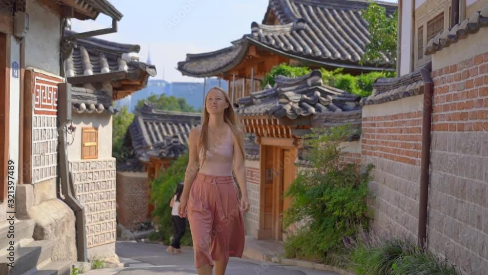 Young woman visits the busy touristic historical street Bukchon Hanok village in a center of Seoul, South Korea. Travel to Korea concept. Slowmotion shot