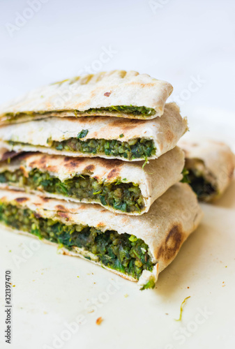 Healthy bread. Flatbread with greens, herbs and spinach filling. Crispy baked or fried food on a plate. Vegan lunch. Turkish gozleme. photo