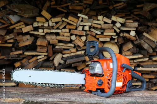  chainsaw is on sawn firewood background.