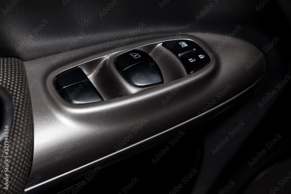 The control buttons for opening and closing windows of doors and electric controls and settings of locks on the door in gray with plastic upholstery in a modern car.