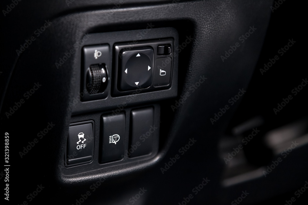 The button for stability control system, side mirrors adjust and headlight washer on black panel of car near the steering wheel to overcome off-road, impassable roads and drive safely in snow or rain