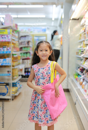 Happy girl shopping in department store with carrying a pink recycle bag (spun ball bag). Eco friendly bag for reduce or zero waste concept