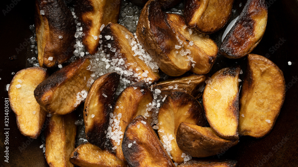 Baked potato wedges with coarse salt. Fast food, rustic food Baked potato wedges with coarse salt. Fast food, rustic food