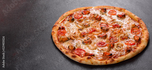 Tasty sliced pizza with seafood and tomato on a concrete background