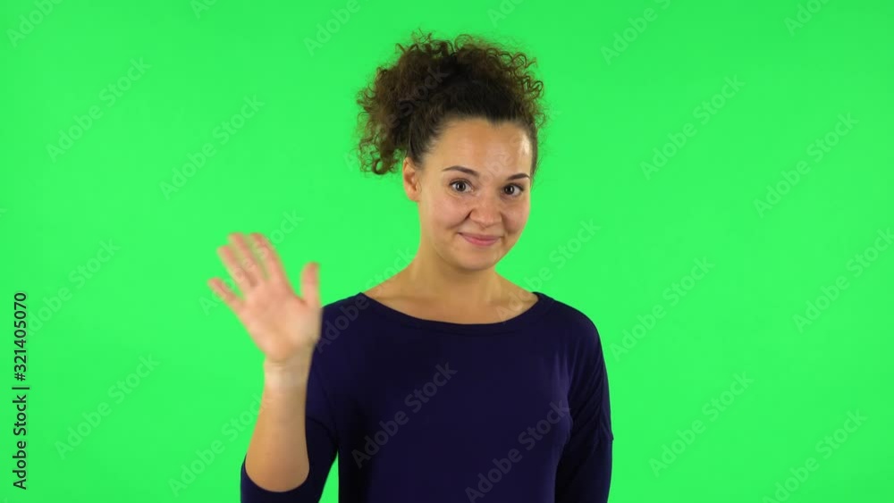 Portrait of curly woman waving hand and showing gesture come here. Green screen