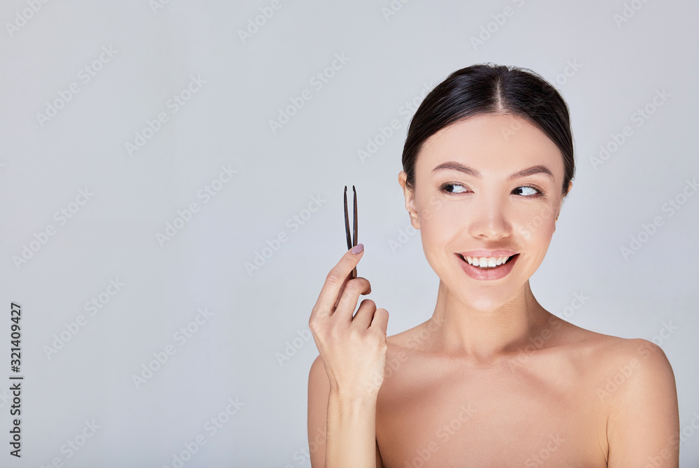 A cute Asian woman holds tweezers in her hands. A cute Asian woman holds tweezers in her hands.