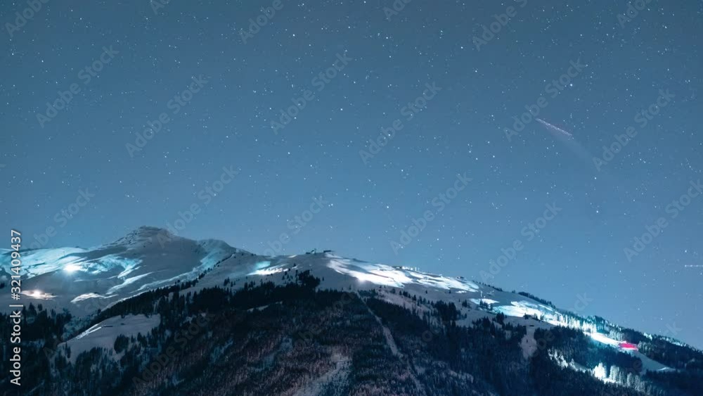 Timelapse of snowcats grooming the slopes of a ski resort at night under a night sky with moving stars Timelapse of snowcats grooming the slopes of a ski resort at night under a night sky with moving stars