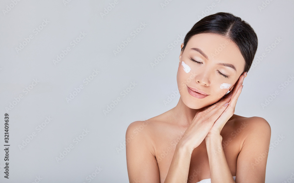 Delicate romantic Asian woman with cream on her face closed her eyes. Delicate romantic Asian woman with cream on her face closed her eyes.