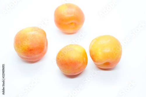 Ripe orange plums perched on a white background