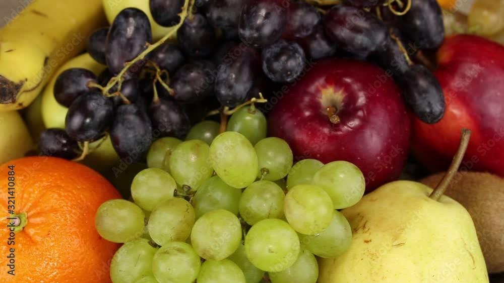 Orange, green grapes, pear, red apples and kiwi rotate clockwise, top view, close-up Orange, green grapes, pear, red apples and kiwi rotate clockwise, top view, close-up