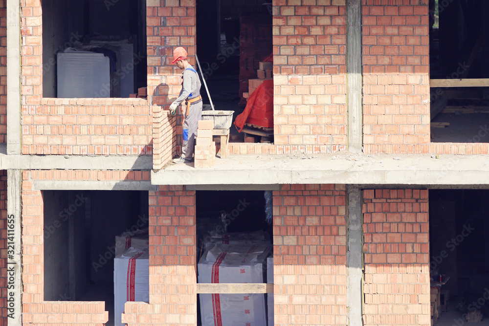 Men workers on constaction laying bricks , building new floor.