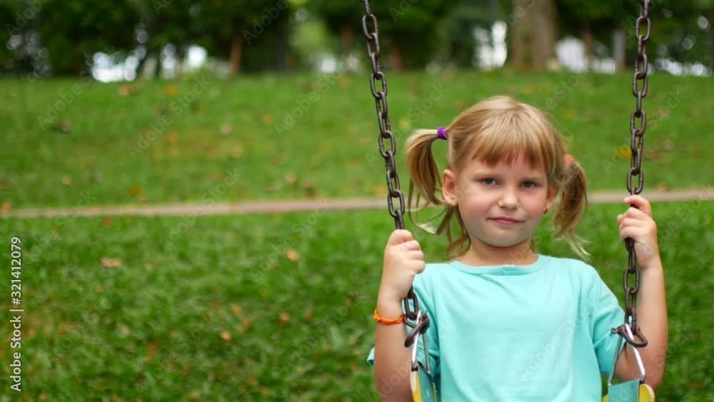 Child girl riding a swing in the park Child girl riding a swing in the park