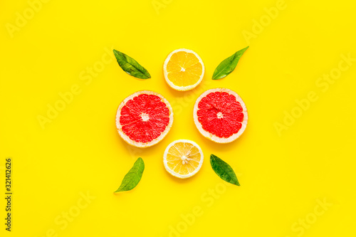 Fototapeta Naklejka Na Ścianę i Meble -  Citrus pattern. Lemon and grapefruits slices and leaves on yellow background top-down