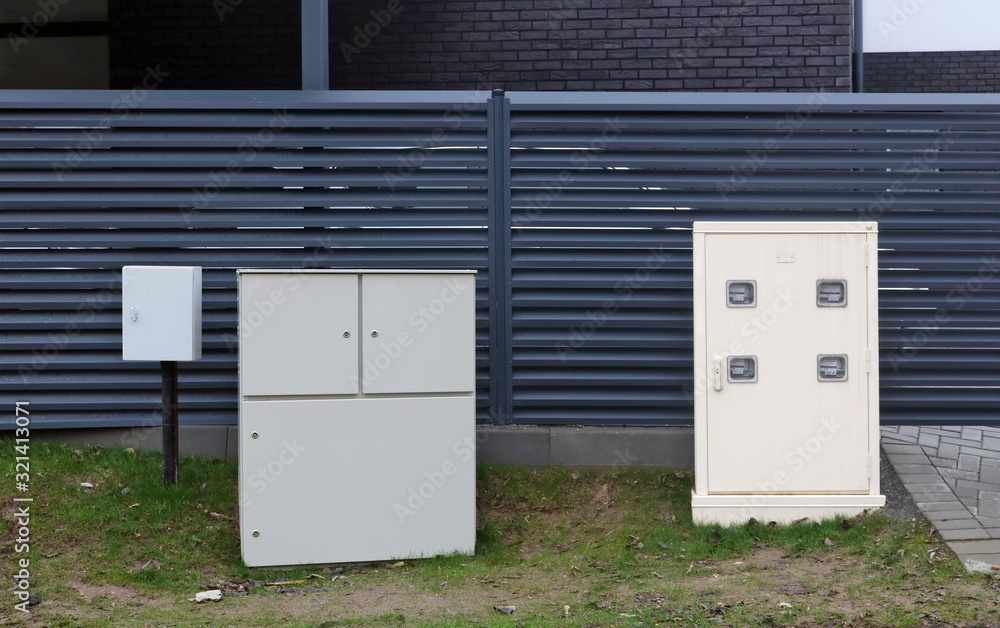 Metal boxes with electricity and natural gas counters meters are installed near the rural house