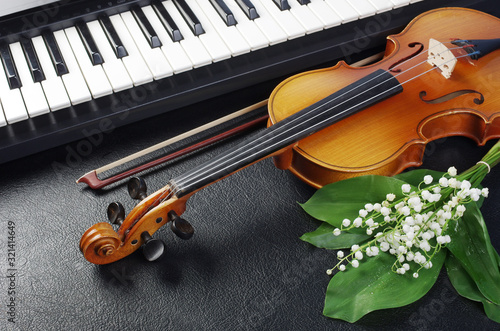 Keyboard, violin with a bow and a bouquet of lilies of the valley