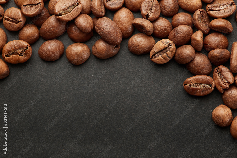 Naklejka premium Brown roasted coffee beans on dark background. Espresso dark, aroma, black caffeine drink. Closeup isolated energy mocha, cappuccino ingredient.