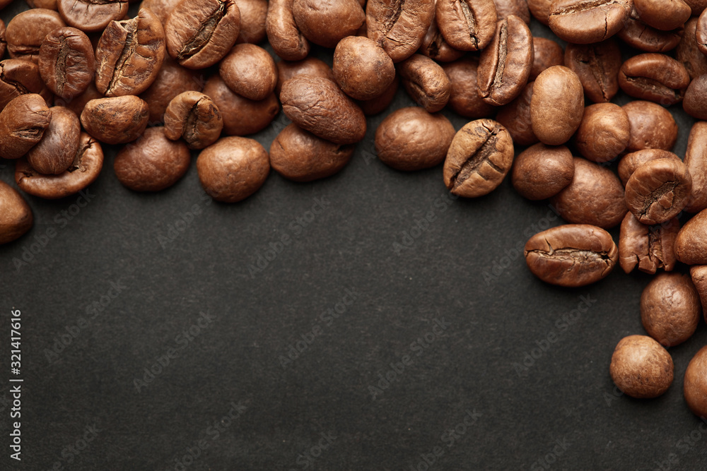 Naklejka premium Brown roasted coffee beans on dark background. Espresso dark, aroma, black caffeine drink. Closeup isolated energy mocha, cappuccino ingredient.
