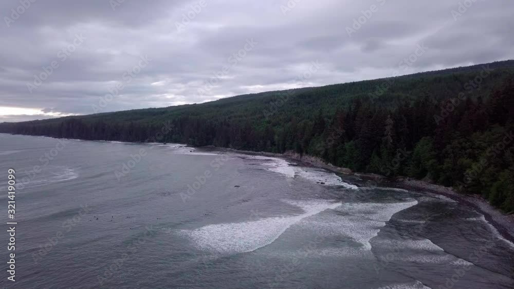 Calm Sea Waves Splashing To The Lush Shore With Green Pine Trees In Vancouver Island Beach In Canada Under The Cloudy Sky - Wide Shot Calm Sea Waves Splashing To The Lush Shore With Green Pine Trees In Vancouver Island Beach In Canada Under The Cloudy Sky - Wide Shot
