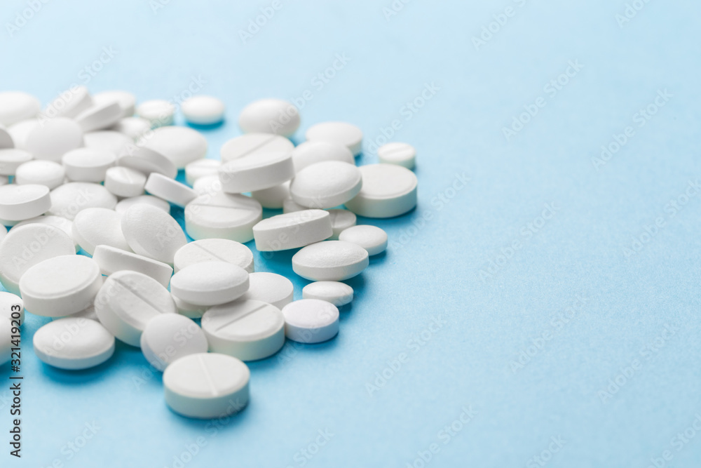 scattered white pills on a blue table. Layout for special offers such as advertising or other ideas. The concept of medicine, pharmacy and healthcare. Space for copy. flat lay for text or logo. scattered white pills on a blue table. Layout for special offers such as advertising or other ideas. The concept of medicine, pharmacy and healthcare. Space for copy. flat lay for text or logo.