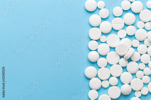 scattered white pills on a blue table. Layout for special offers such as advertising or other ideas. The concept of medicine, pharmacy and healthcare. Space for copy. flat lay for text or logo. photo