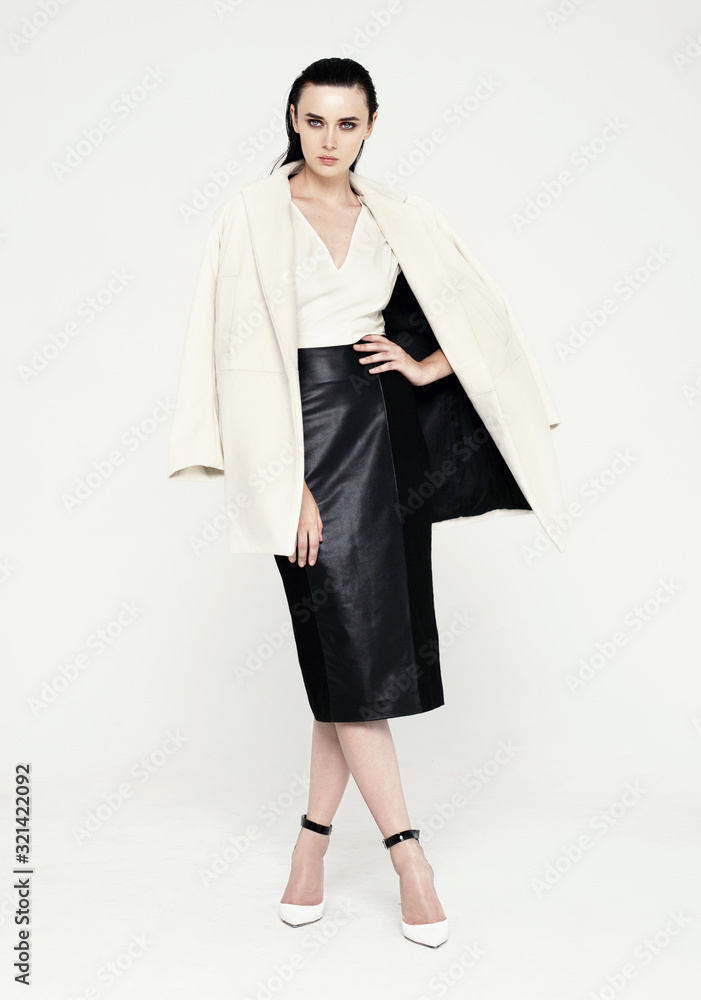 Full length fashion shot of beautiful model in white coat and black skirt. Isolated on white background Full length fashion shot of beautiful model in white coat and black skirt. Isolated on white background