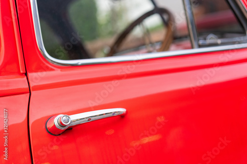 Close-up view of the red vintage car door handle.