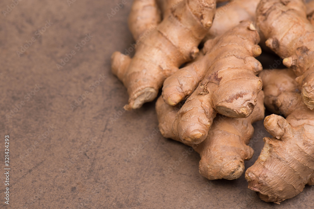 Fresh ginger roots on a brown textured background, empty copy space