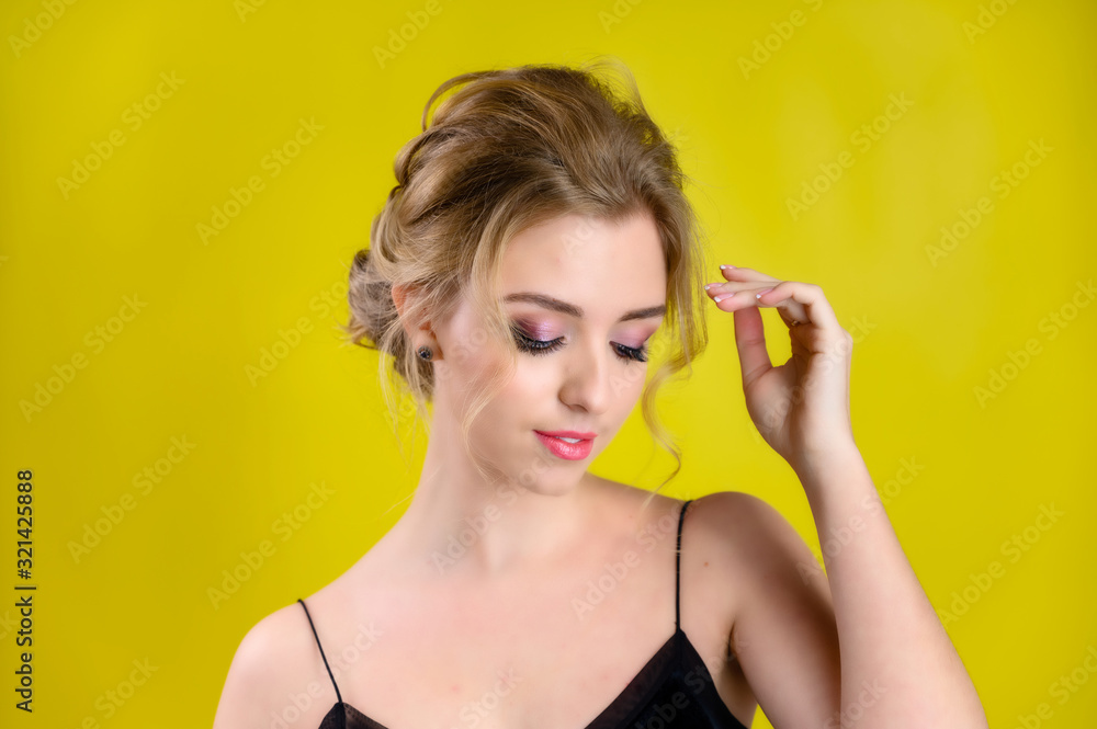 The concept of cosmetics, fashion and style. Glamorous beauty portrait of a pretty blonde model with excellent makeup and a beautiful hairstyle on a yellow background in the studio. The concept of cosmetics, fashion and style. Glamorous beauty portrait of a pretty blonde model with excellent makeup and a beautiful hairstyle on a yellow background in the studio.
