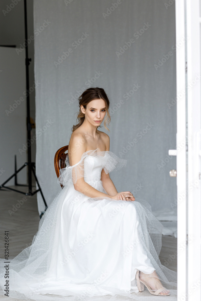 A beautiful young bride in a white dress is sitting on a chair while waiting. A beautiful young bride in a white dress is sitting on a chair while waiting.