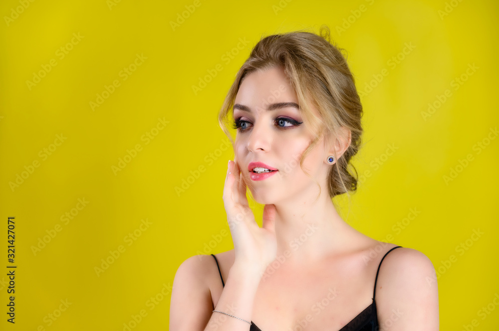 Glamorous beauty front view portrait of a pretty blonde model with excellent make-up and beautiful hairstyle on a yellow background in the studio. The concept of cosmetics, fashion and style. Glamorous beauty front view portrait of a pretty blonde model with excellent make-up and beautiful hairstyle on a yellow background in the studio. The concept of cosmetics, fashion and style.