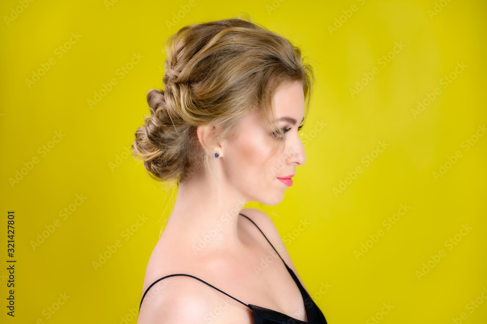 Glamorous beauty portrait side view of a pretty blonde model with excellent makeup and a beautiful hairstyle on a yellow background in the studio. The concept of cosmetics, fashion and style. Glamorous beauty portrait side view of a pretty blonde model with excellent makeup and a beautiful hairstyle on a yellow background in the studio. The concept of cosmetics, fashion and style.