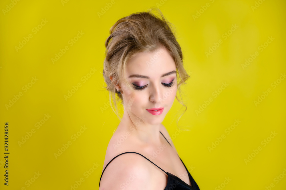 Glamorous beauty portrait side view of a pretty blonde model with excellent makeup and a beautiful hairstyle on a yellow background in the studio. The concept of cosmetics, fashion and style. Glamorous beauty portrait side view of a pretty blonde model with excellent makeup and a beautiful hairstyle on a yellow background in the studio. The concept of cosmetics, fashion and style.