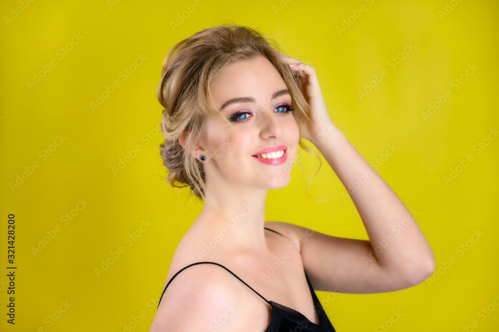Glamorous beauty portrait side view of a pretty blonde model with excellent makeup and a beautiful hairstyle on a yellow background in the studio. The concept of cosmetics, fashion and style. Glamorous beauty portrait side view of a pretty blonde model with excellent makeup and a beautiful hairstyle on a yellow background in the studio. The concept of cosmetics, fashion and style.