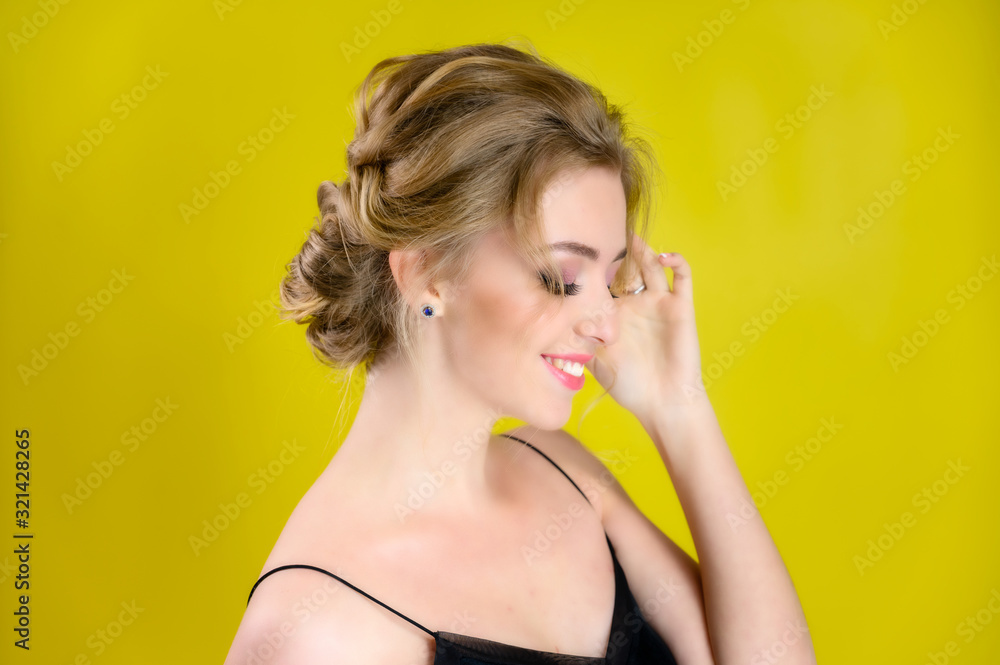Glamorous beauty portrait side view of a pretty blonde model with excellent makeup and a beautiful hairstyle on a yellow background in the studio. The concept of cosmetics, fashion and style. Glamorous beauty portrait side view of a pretty blonde model with excellent makeup and a beautiful hairstyle on a yellow background in the studio. The concept of cosmetics, fashion and style.