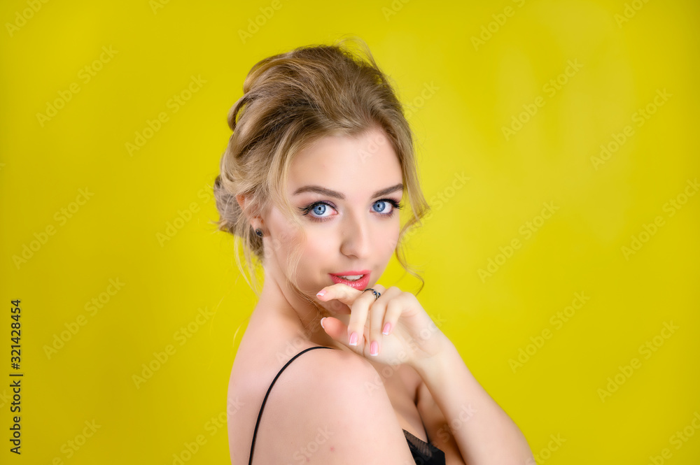 Glamorous beauty portrait side view of a pretty blonde model with excellent makeup and a beautiful hairstyle on a yellow background in the studio. The concept of cosmetics, fashion and style. Glamorous beauty portrait side view of a pretty blonde model with excellent makeup and a beautiful hairstyle on a yellow background in the studio. The concept of cosmetics, fashion and style.