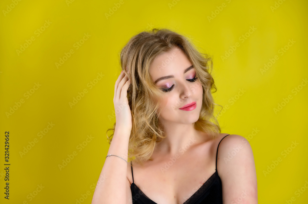 Glamorous beauty front view portrait of a pretty model with blond hair with great makeup and a beautiful hairstyle on a yellow background in the studio. The concept of cosmetics, fashion and style. Glamorous beauty front view portrait of a pretty model with blond hair with great makeup and a beautiful hairstyle on a yellow background in the studio. The concept of cosmetics, fashion and style.