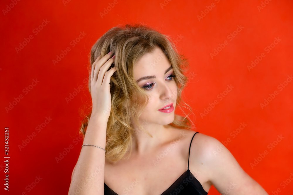 Glamorous beauty front view portrait of a pretty model with blond hair with great makeup and a beautiful hairstyle on a red background in the studio. The concept of cosmetics, fashion and style. Glamorous beauty front view portrait of a pretty model with blond hair with great makeup and a beautiful hairstyle on a red background in the studio. The concept of cosmetics, fashion and style.