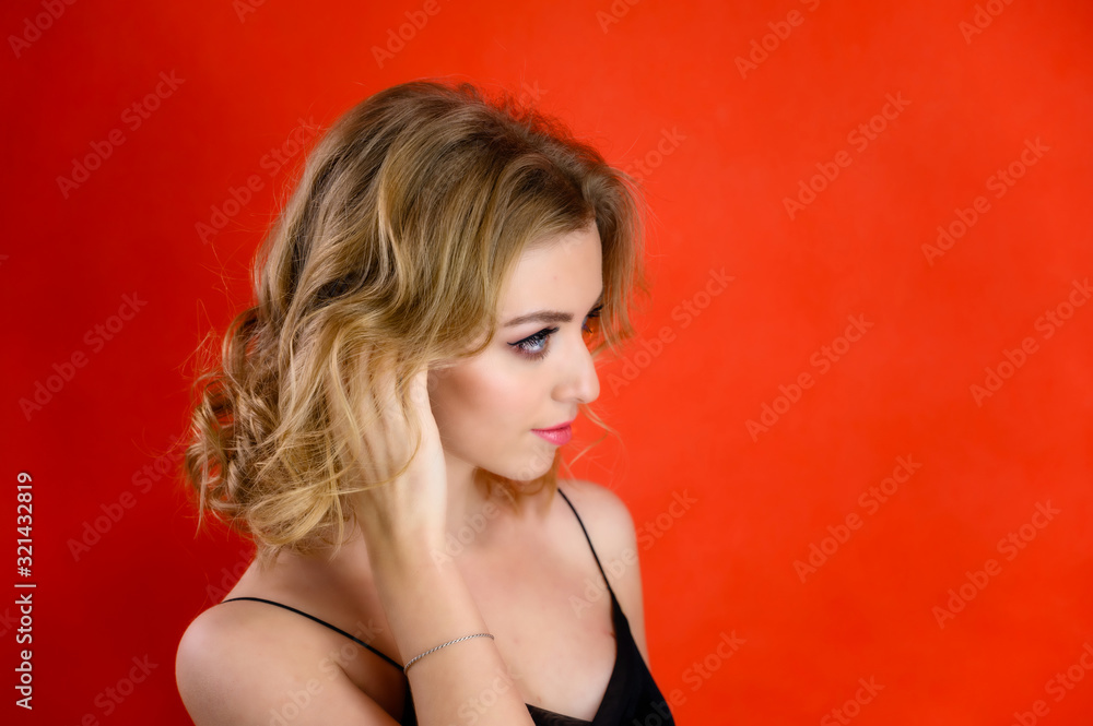 Glamorous beauty portrait side view of a pretty model with blond hair with great makeup and a beautiful hairstyle on a red background in the studio. The concept of cosmetics, fashion and style. Glamorous beauty portrait side view of a pretty model with blond hair with great makeup and a beautiful hairstyle on a red background in the studio. The concept of cosmetics, fashion and style.