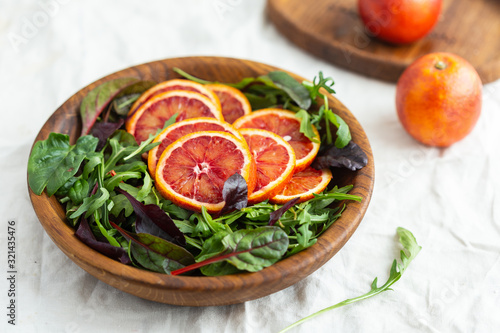A wooden bowl full of fruits and greens
