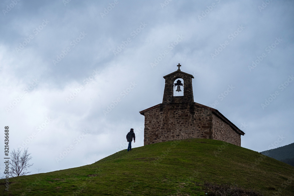hombre aproximandose a una capilla en un cerro