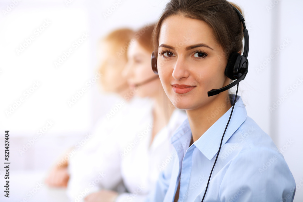 Call center. Focus on beautiful business woman using headset in sunny office Call center. Focus on beautiful business woman using headset in sunny office
