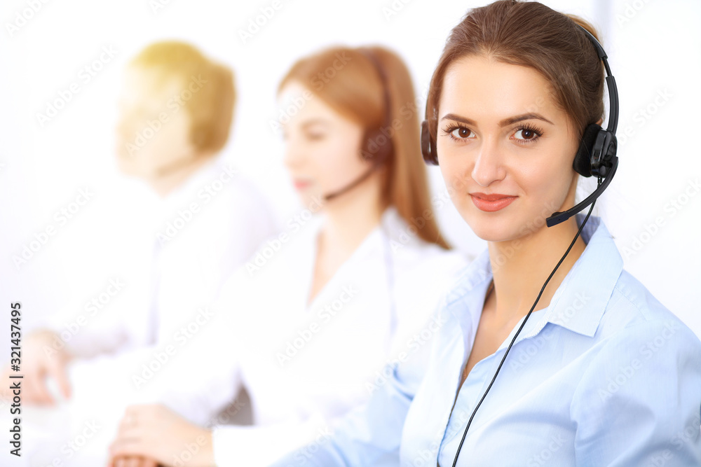 Call center. Focus on beautiful business woman using headset in sunny office Call center. Focus on beautiful business woman using headset in sunny office