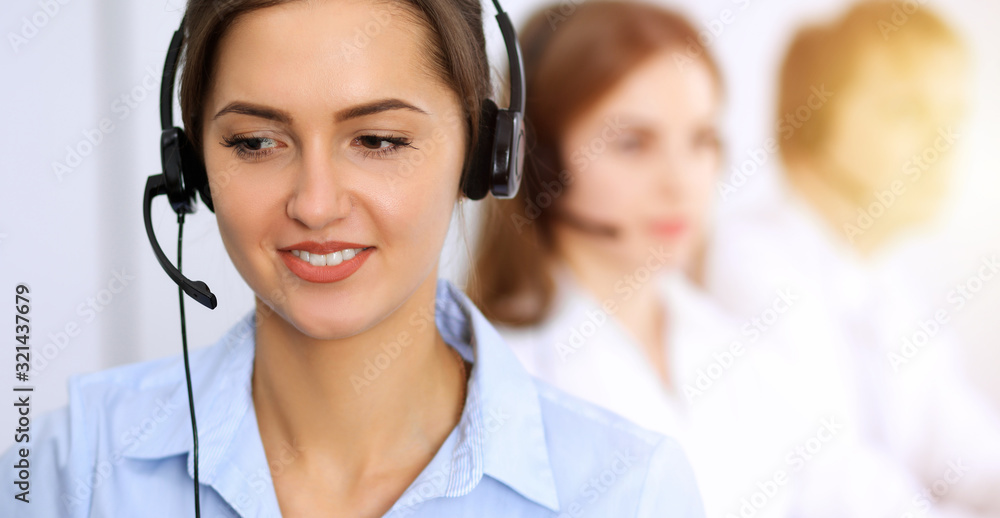 Call center. Focus on beautiful business woman using headset in sunny office Call center. Focus on beautiful business woman using headset in sunny office