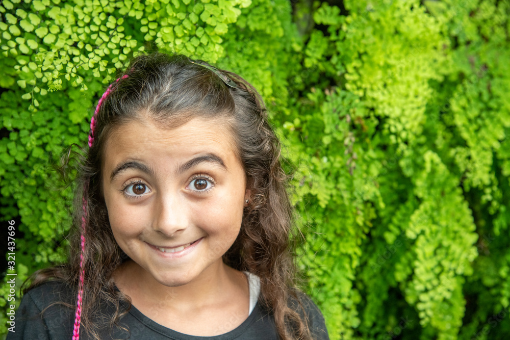 Happy girl framed by green vegetation. Nature and sustainability concept Happy girl framed by green vegetation. Nature and sustainability concept